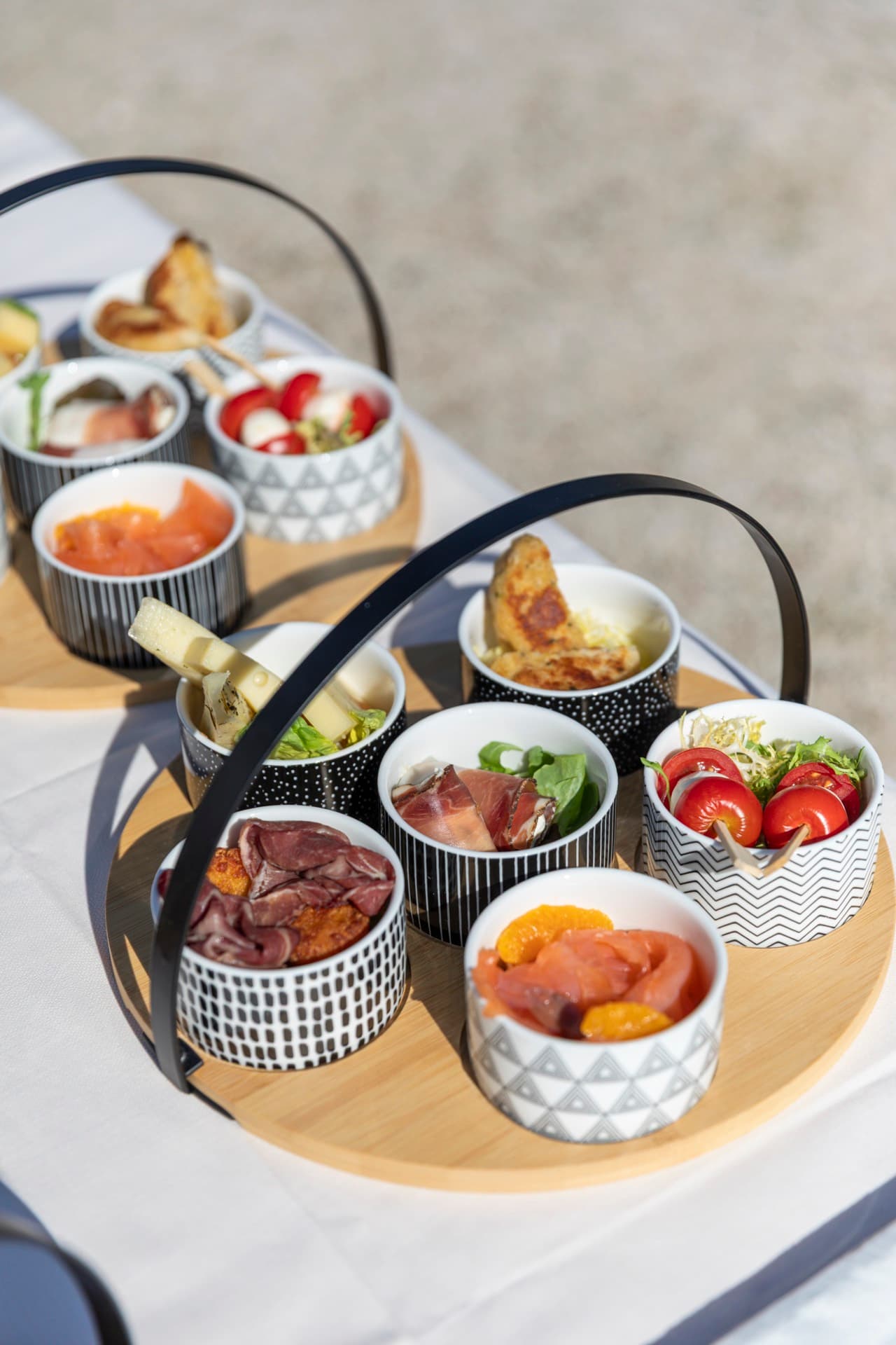 Vassoio in legno con ciotoline di antipasti altoatesini: speck, formaggi, verdure e frutta fresca.